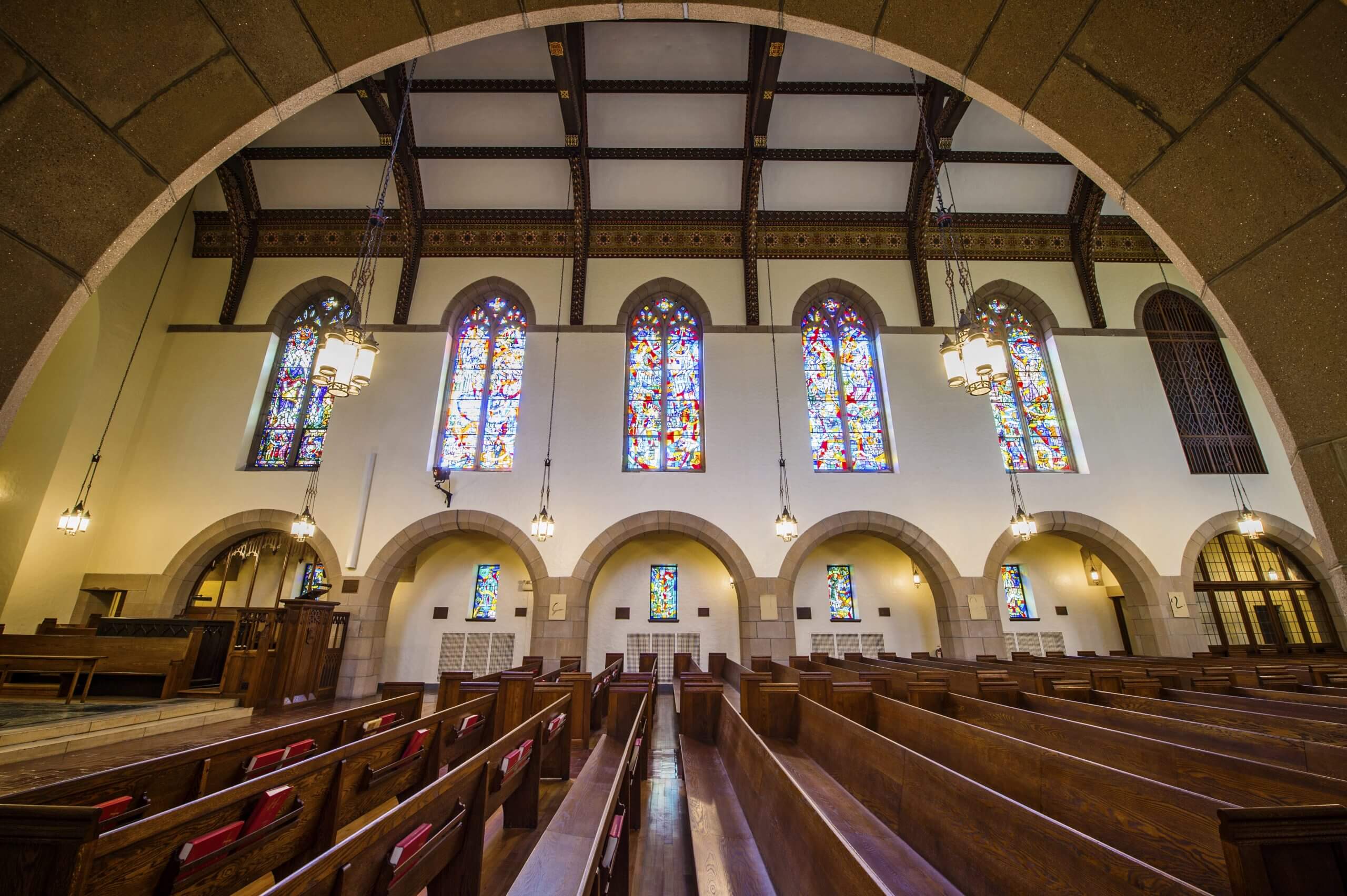 Chapel interior looking through arched doorway at large stained glass windows