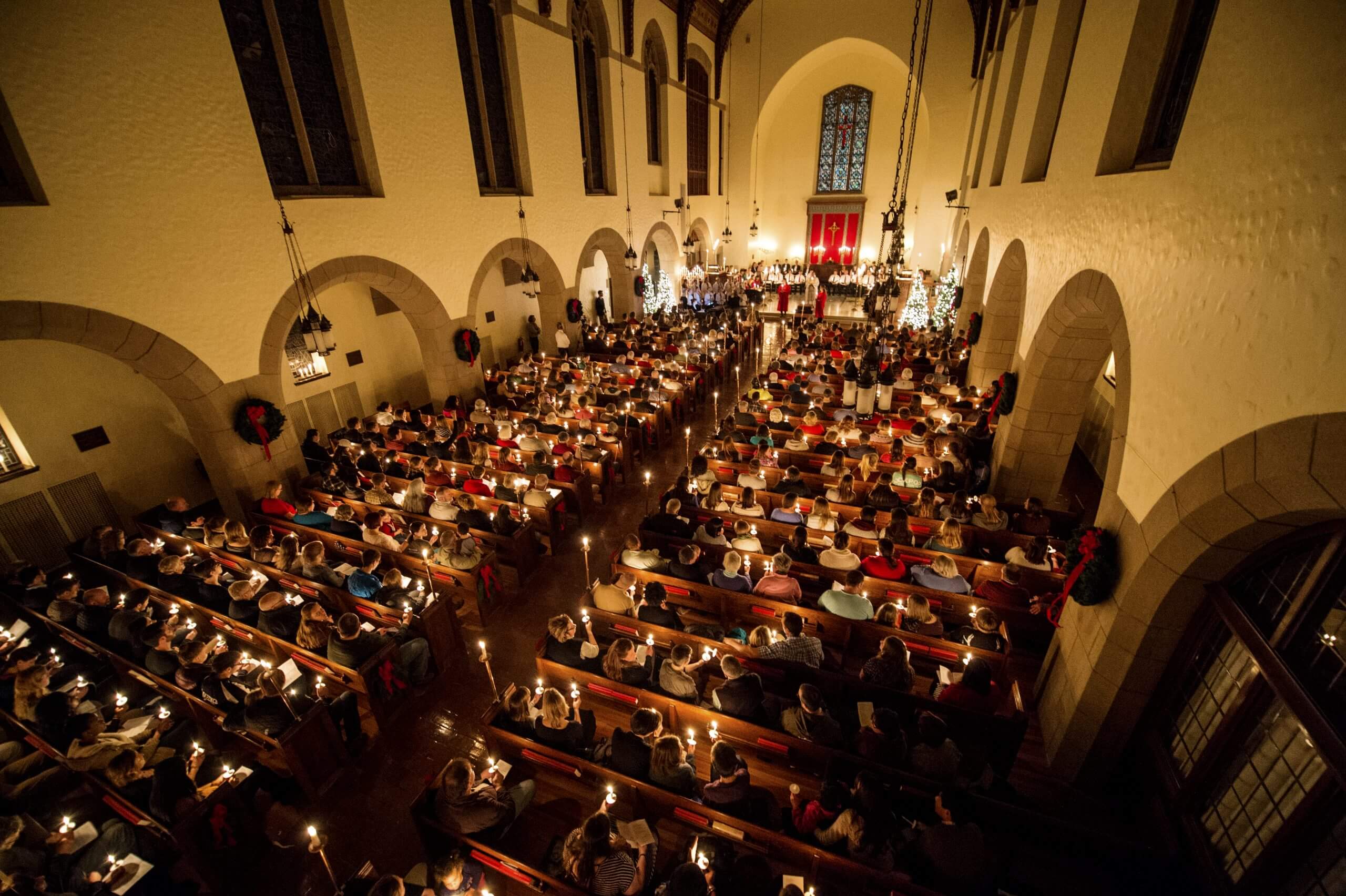 Overhead look at chapel filled with students holding candles during University ceremony