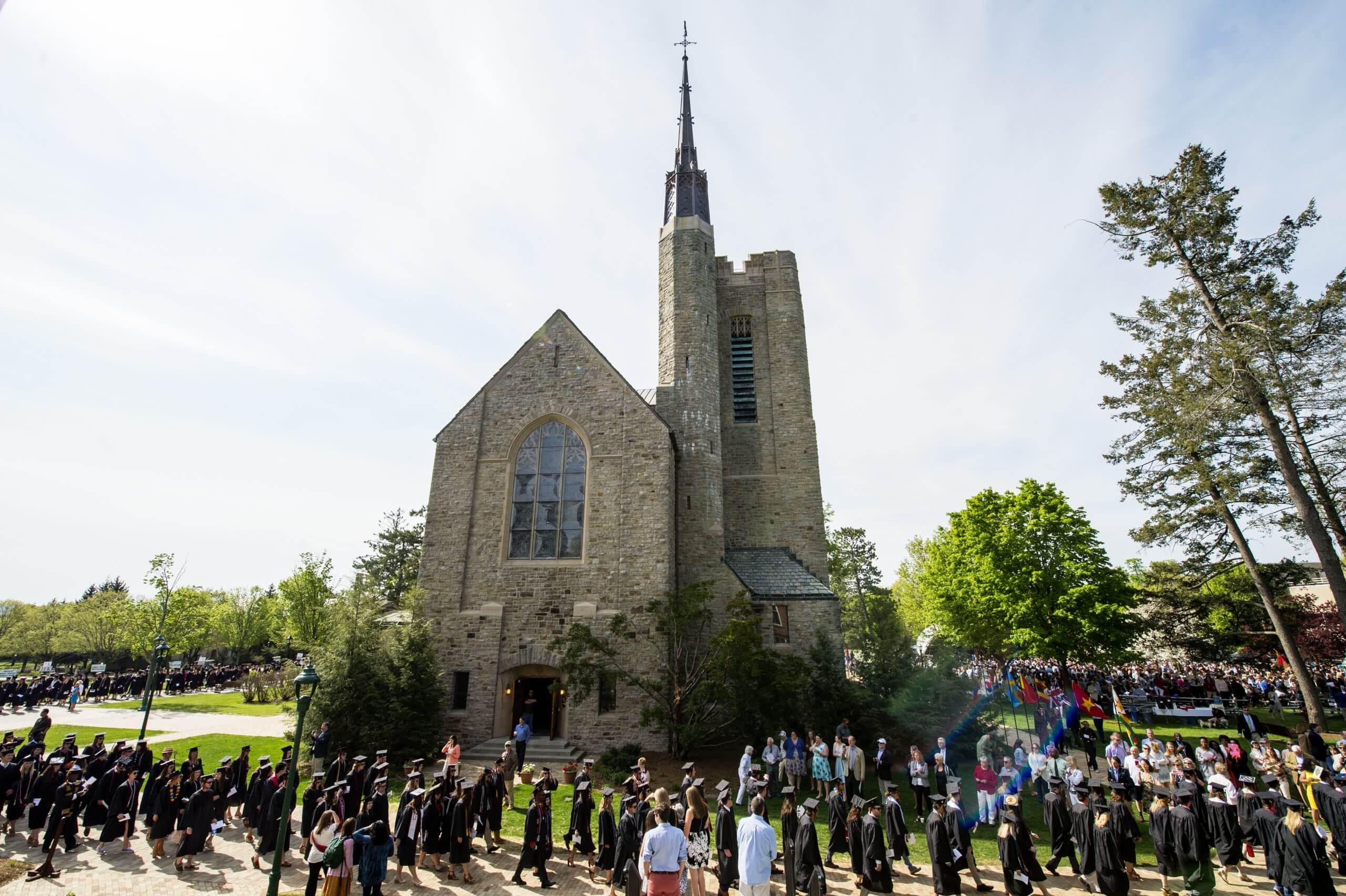 Chapel exterior with students in caps and gowns surrounding the building