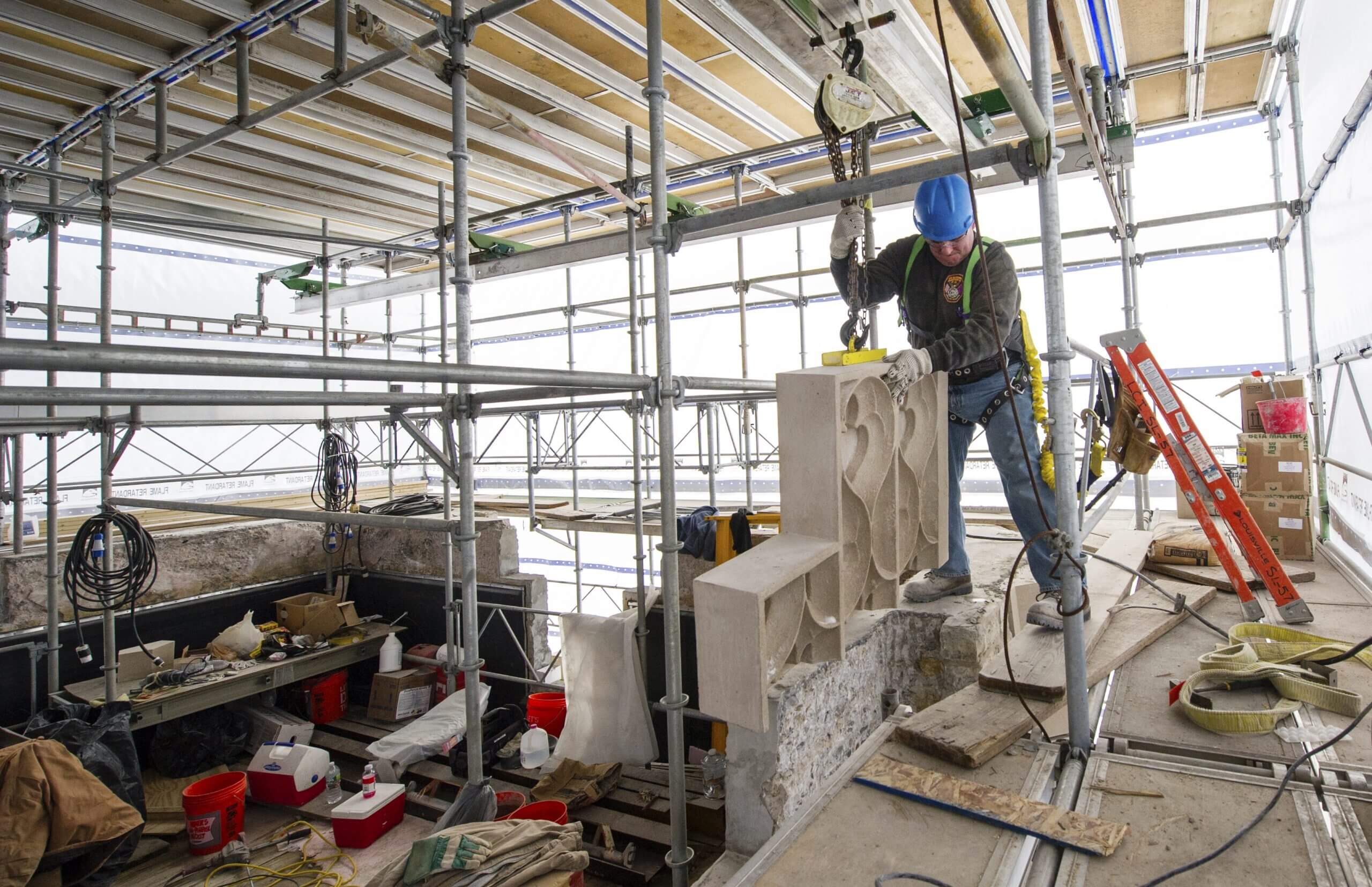 Construction worker installing large stone piece