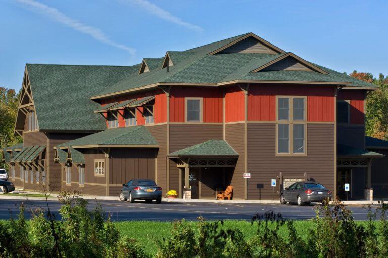 exterior of large healthcare building with brown siding and green shingles