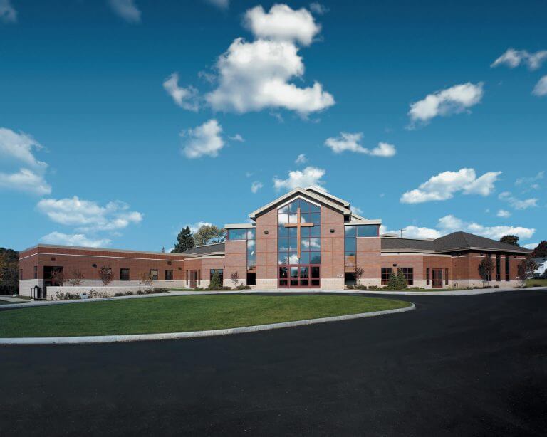 parking lot view of large church with cross above entrance
