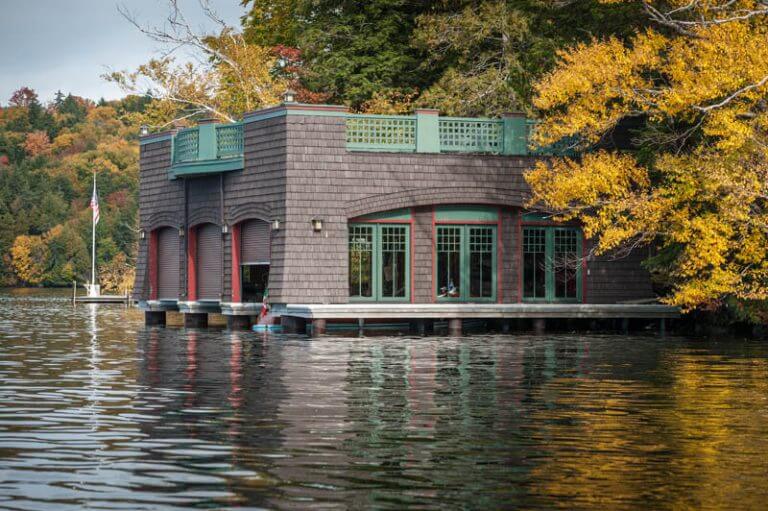 brown shingled boathouse on a lake