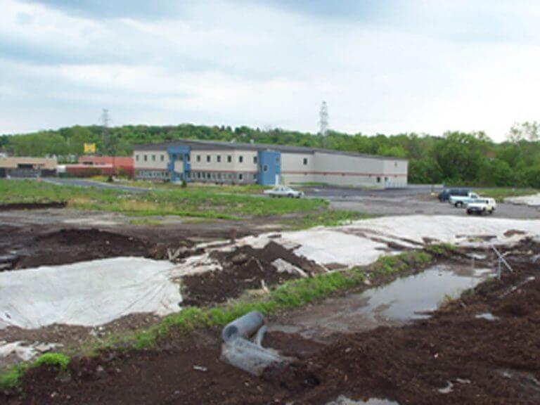 Large office building with vehicles parked in front for site investigation